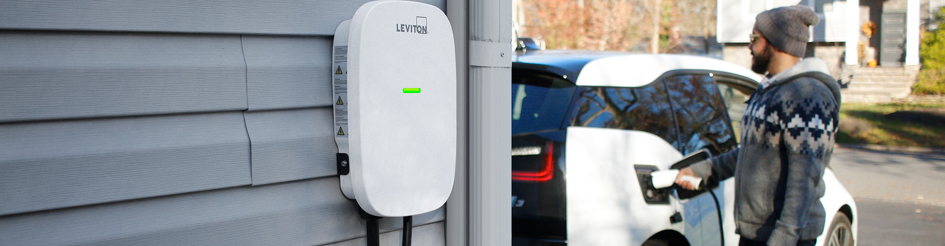 Hombre cargando un vehículo eléctrico en una entrada para autos