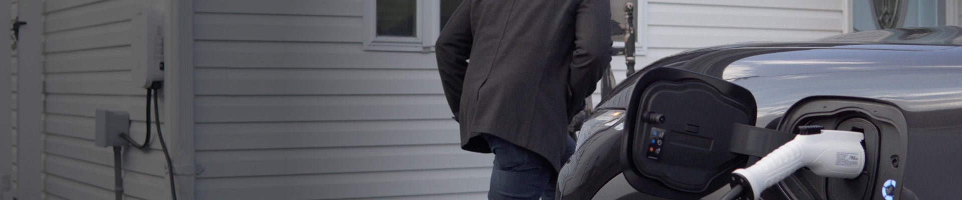 EV en primer plano con cargador serie EV en segundo plano en un hogar